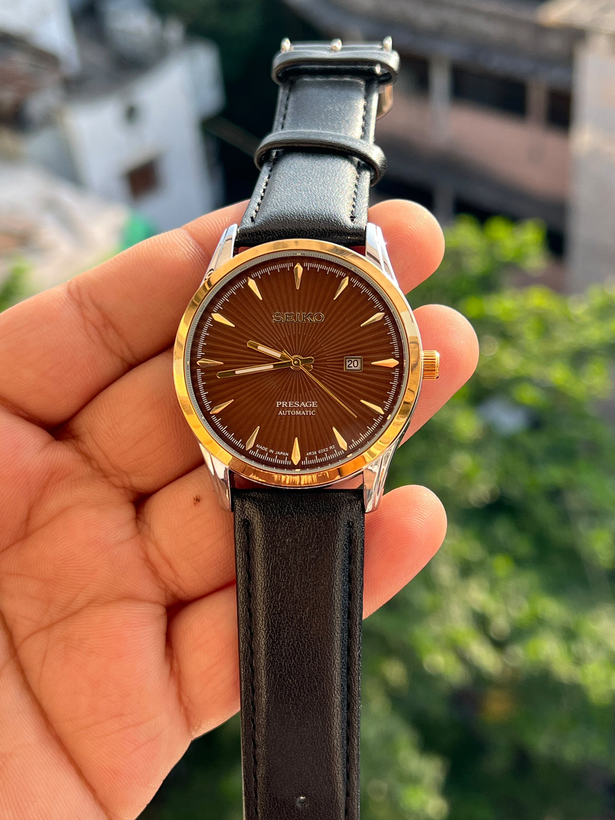 Brown dial Seiko-inspired watch with gold-tone bezel and black strap